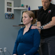 Pregnant patient sitting on an adjustment table being examined by the chiropractor for misalignments in her spine.