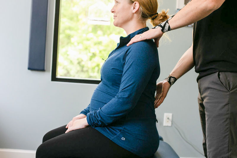 Chiropractor assesses spine of pregnant woman prior to adjusting her